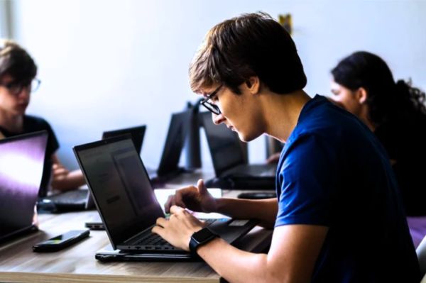 Homem branco digitando no computador em um escritório